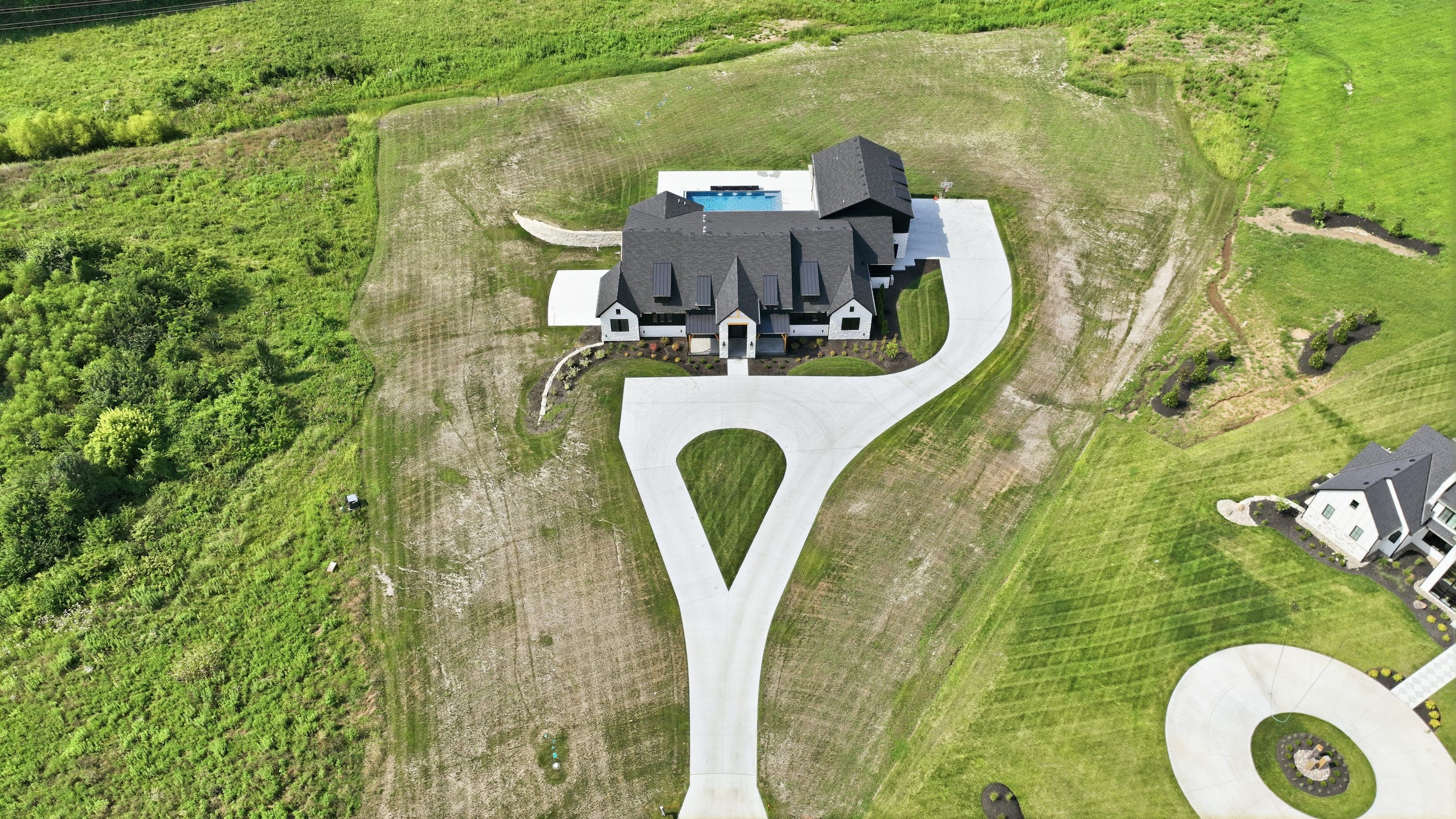 Aerial photo of a modern farmhouse on acreage with a circular drive