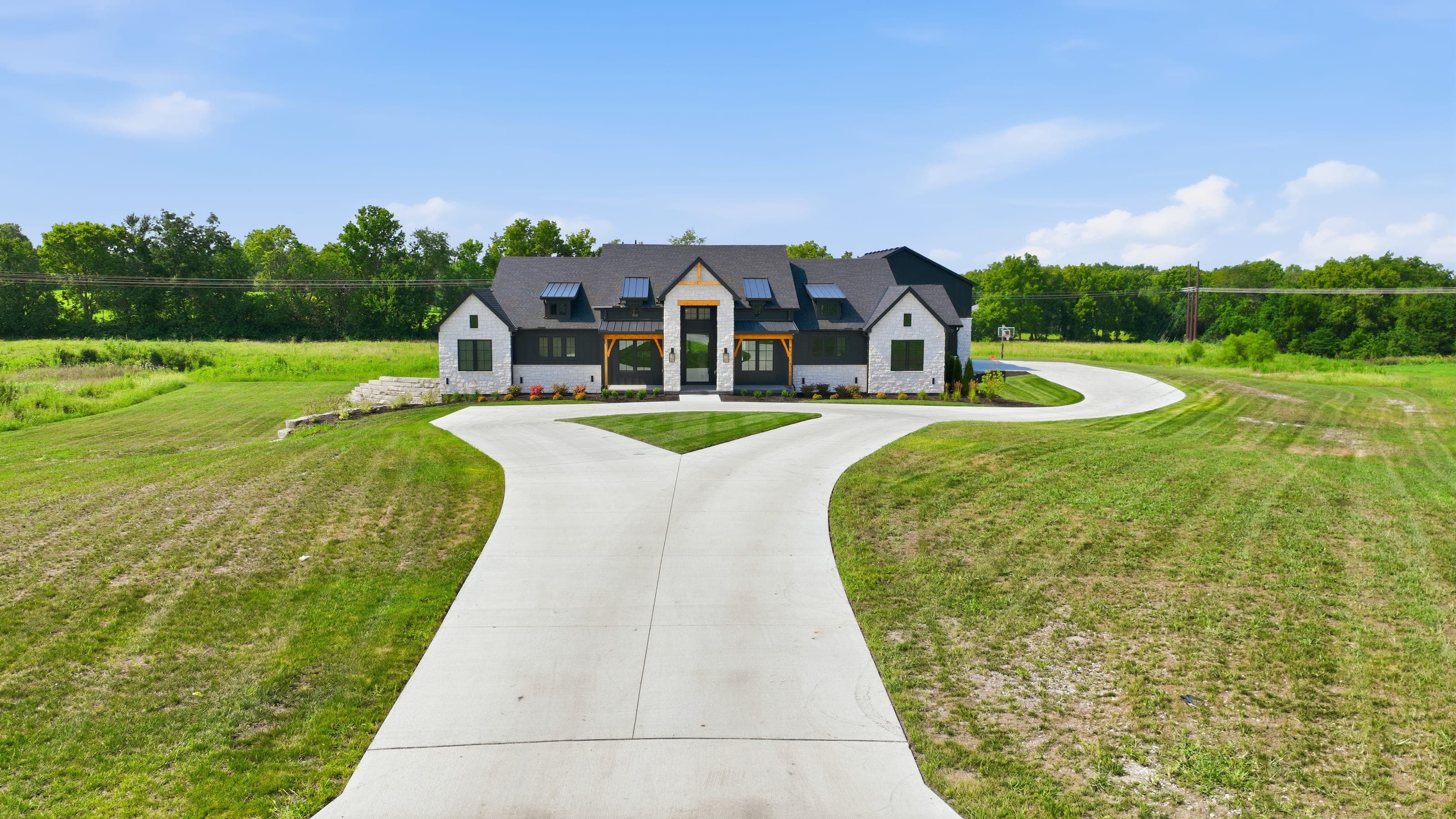 Aerial view of a white stone and black farmhouse with a long drive
