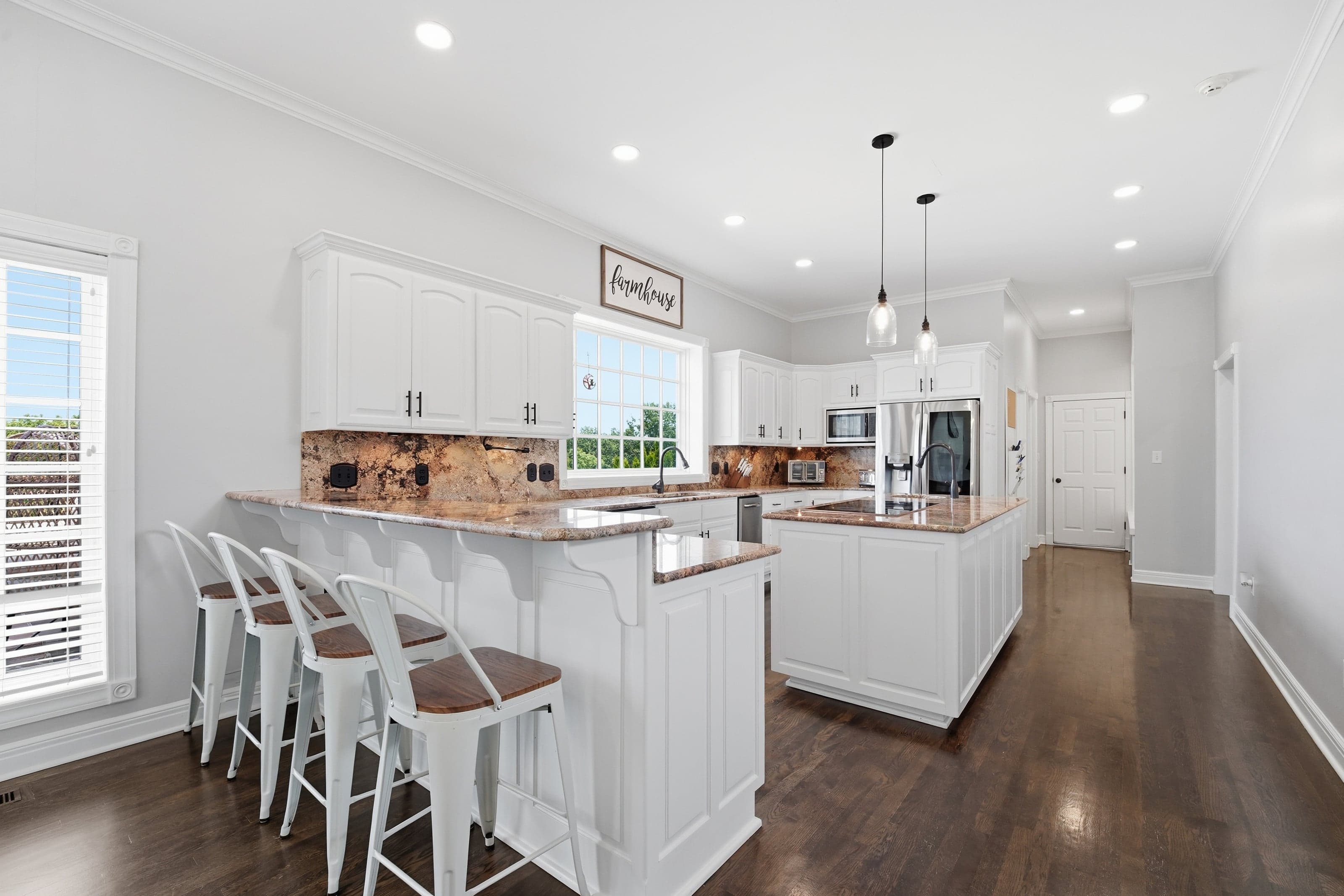 White farmhouse-style kitchen with a wood-topped island and a "farmhouse" sign