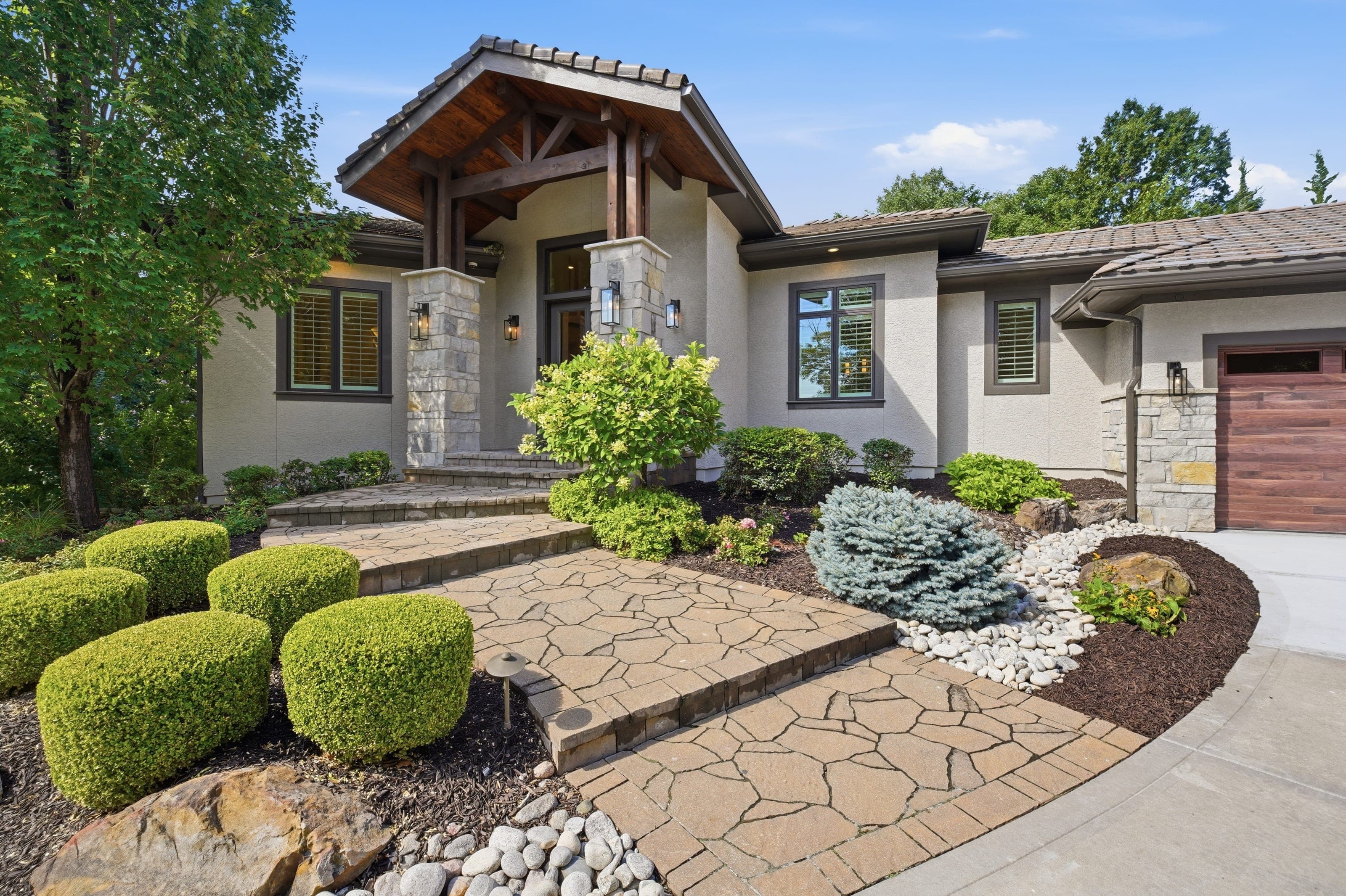Stone and stucco home exterior with timber entry and landscaped walkway