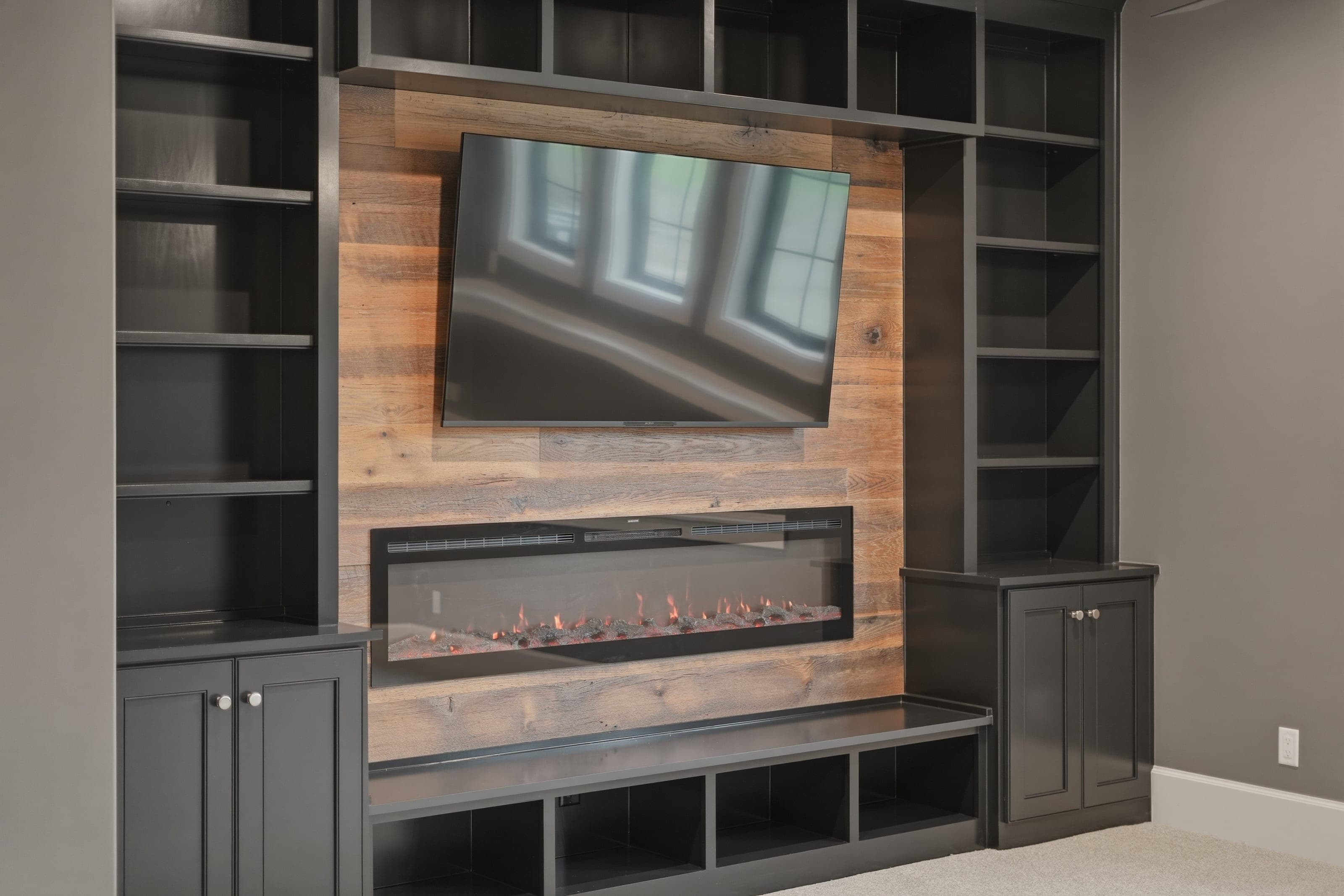 Lower level built-ins with a linear fireplace and reclaimed wood surround