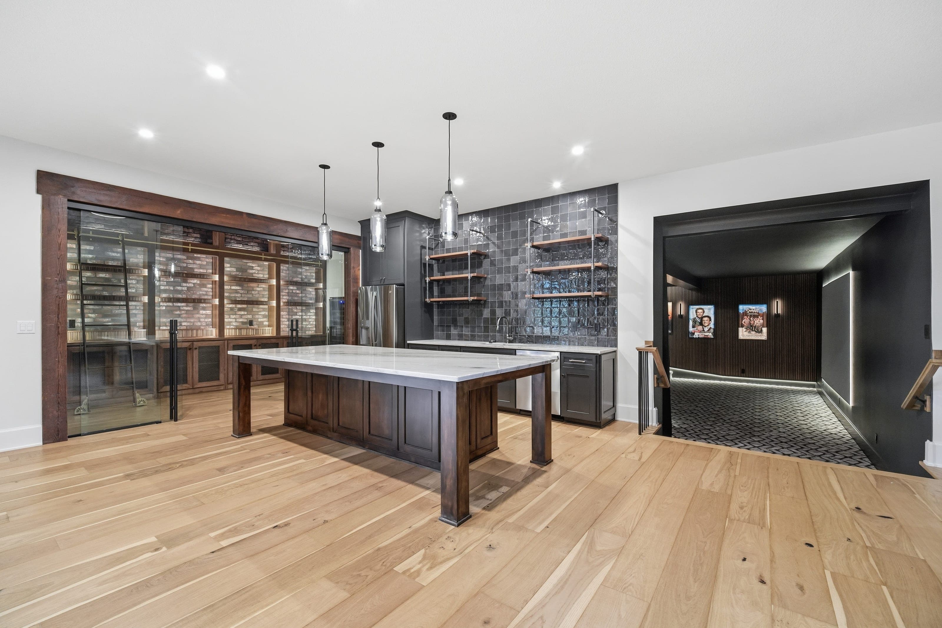 Lower level bar and wine room with a home theater beyond