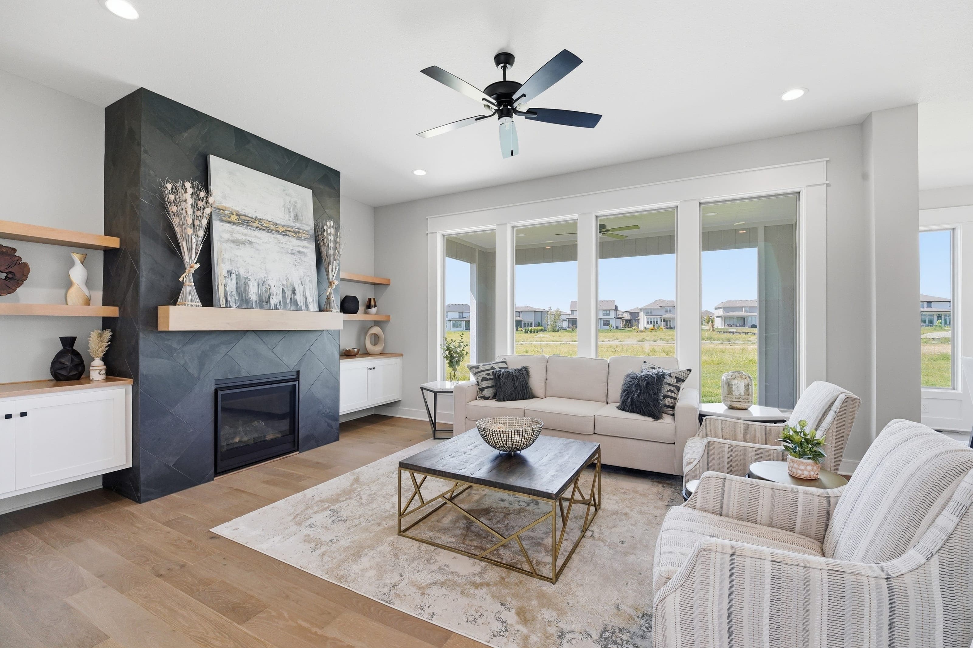Living room with slate fireplace, floating shelves and a wall of windows