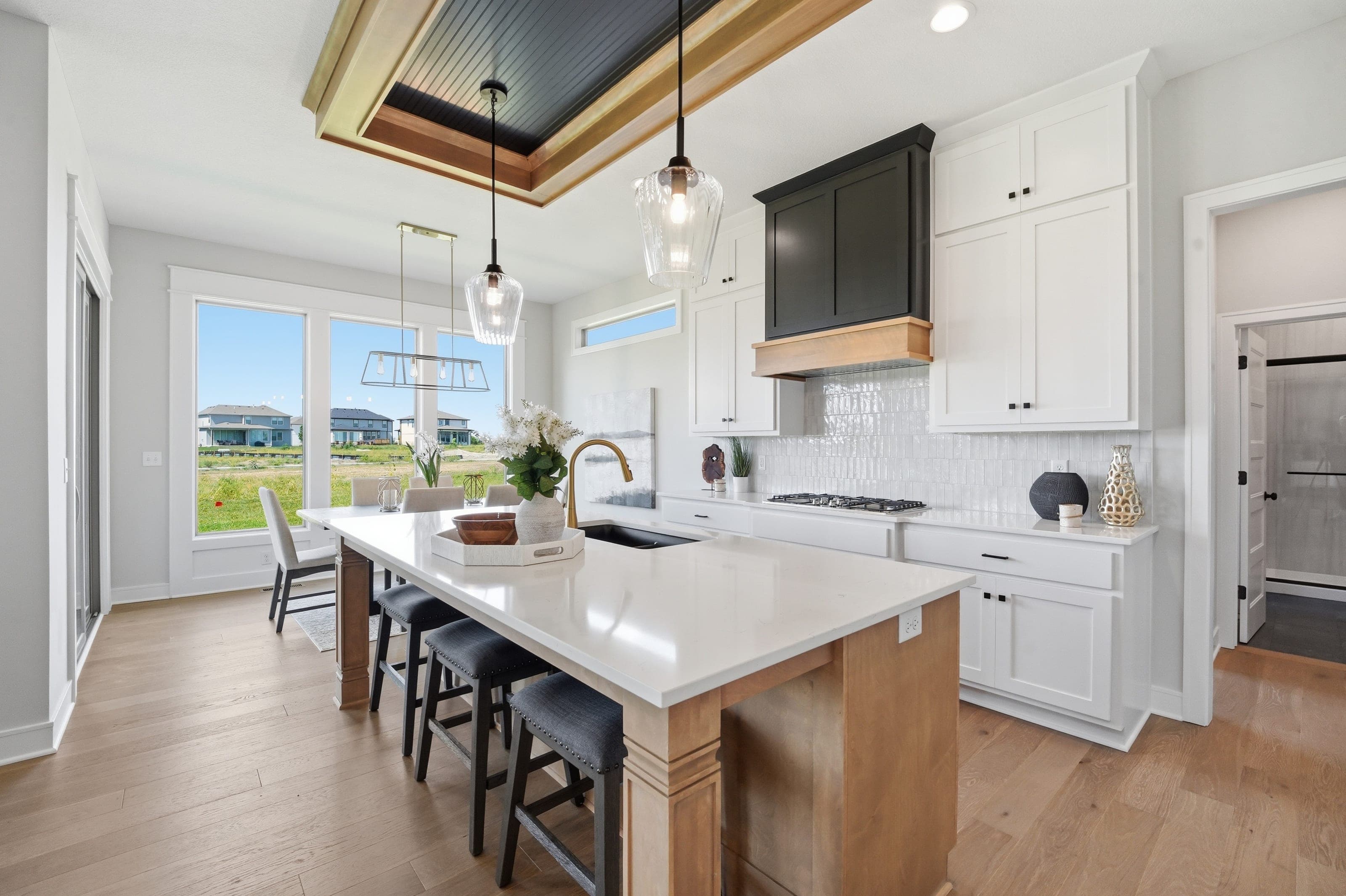 Kitchen with white cabinetry, black hood and a tray ceiling