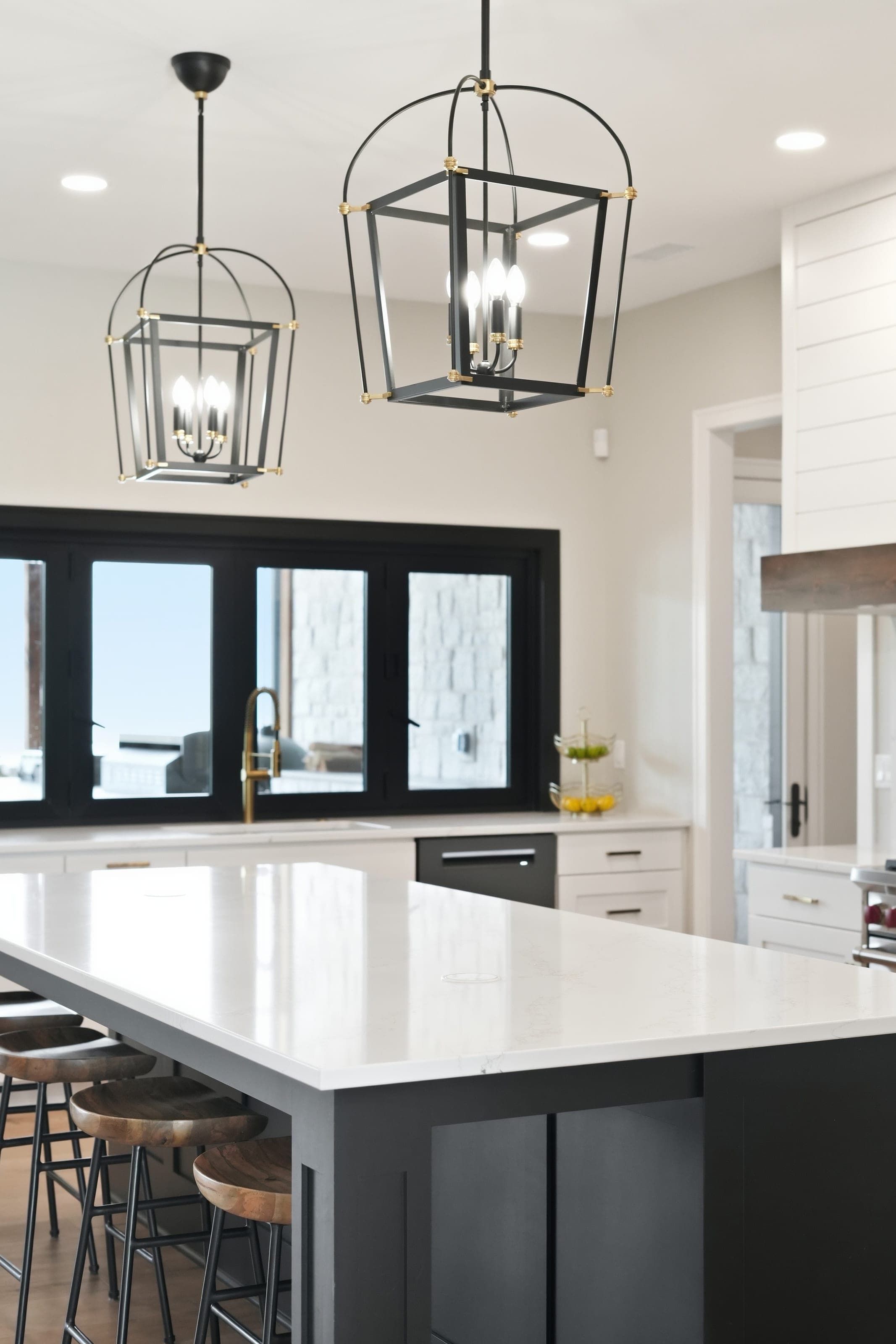 Quartz kitchen island beneath black lantern pendants