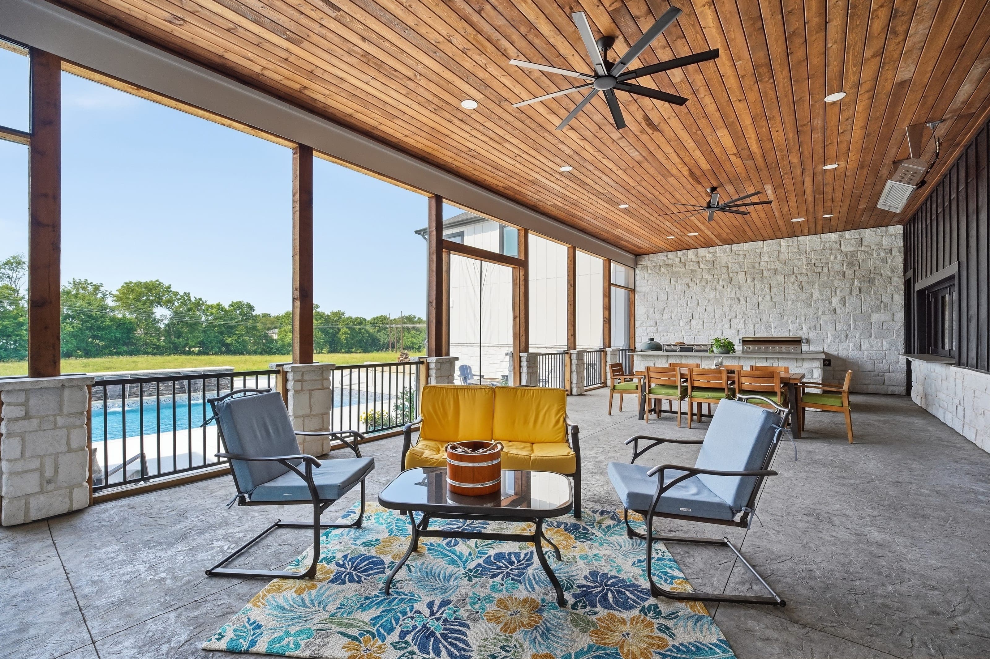 Covered outdoor living area with wood ceiling overlooking a pool