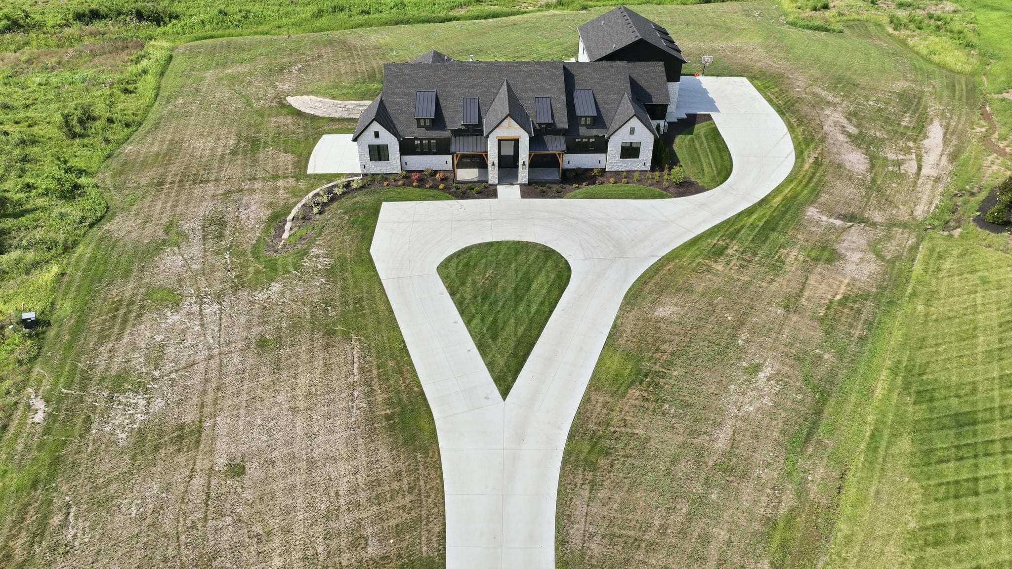 Aerial down the concrete drive to the front elevation