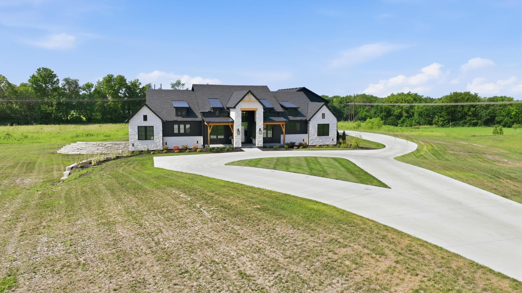 Wide low aerial of the farmhouse and its Y-shaped drive across open acreage