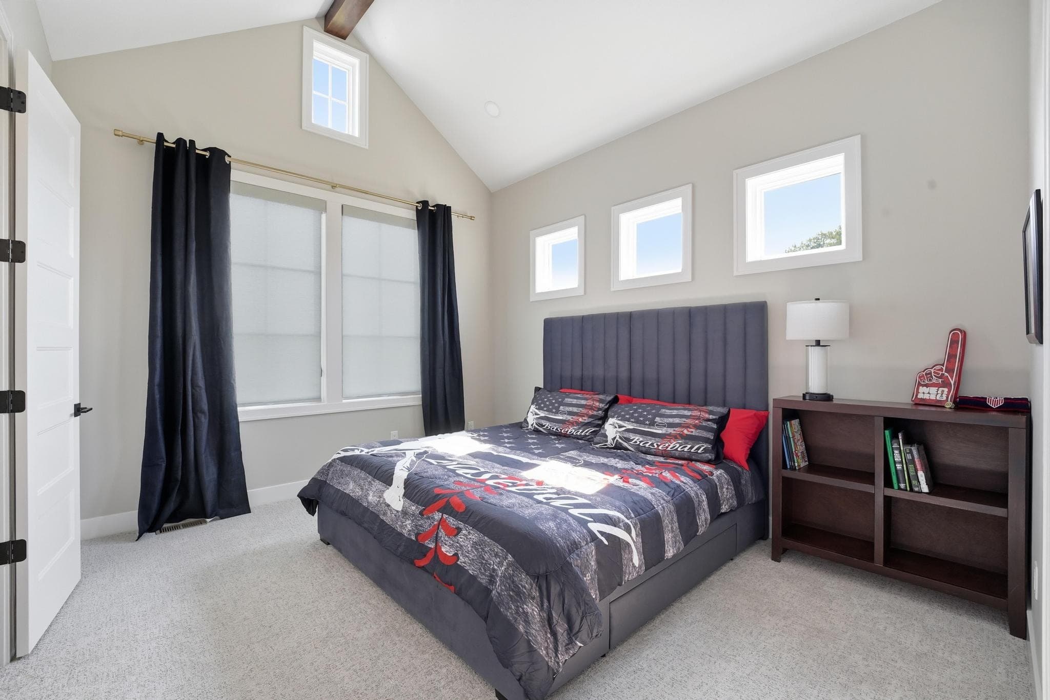 Bedroom with an upholstered headboard and black curtains