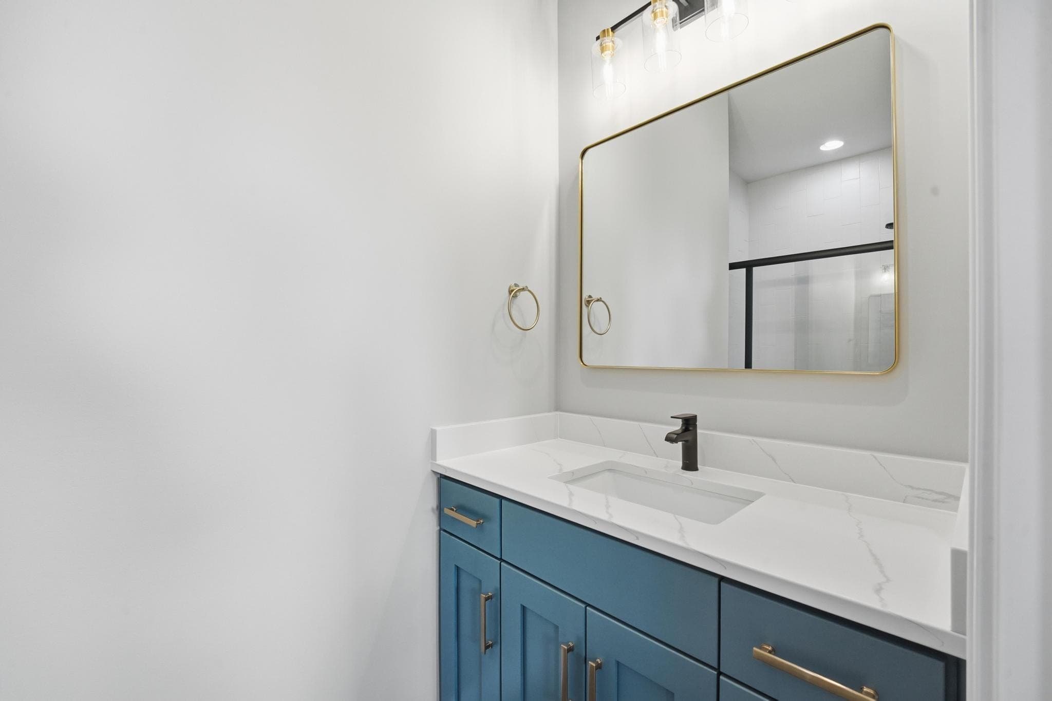 Ensuite bath with a blue vanity and brass fixtures