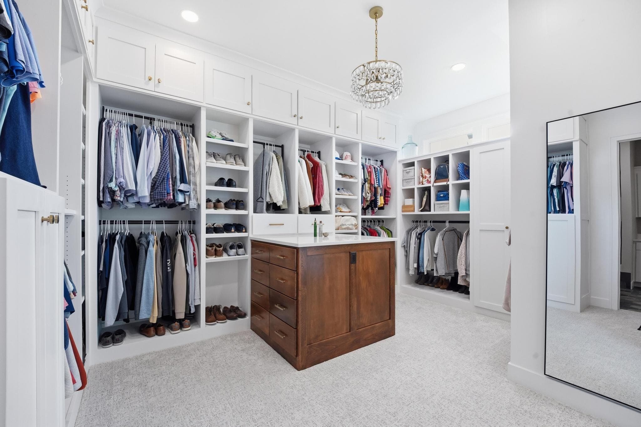 Walk-in primary closet with a wood island