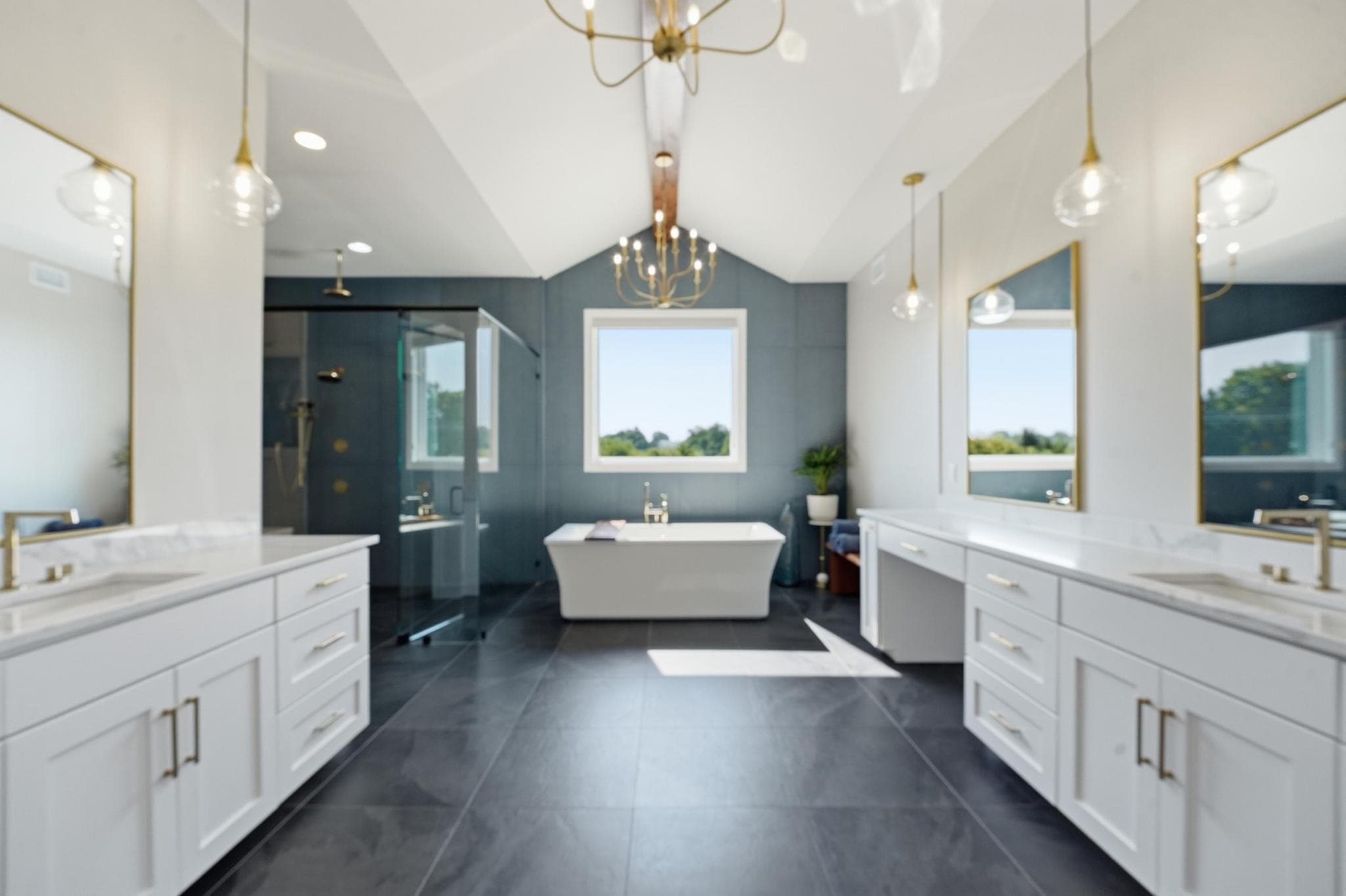 Primary bath with blue tile wall, freestanding tub and double vanities