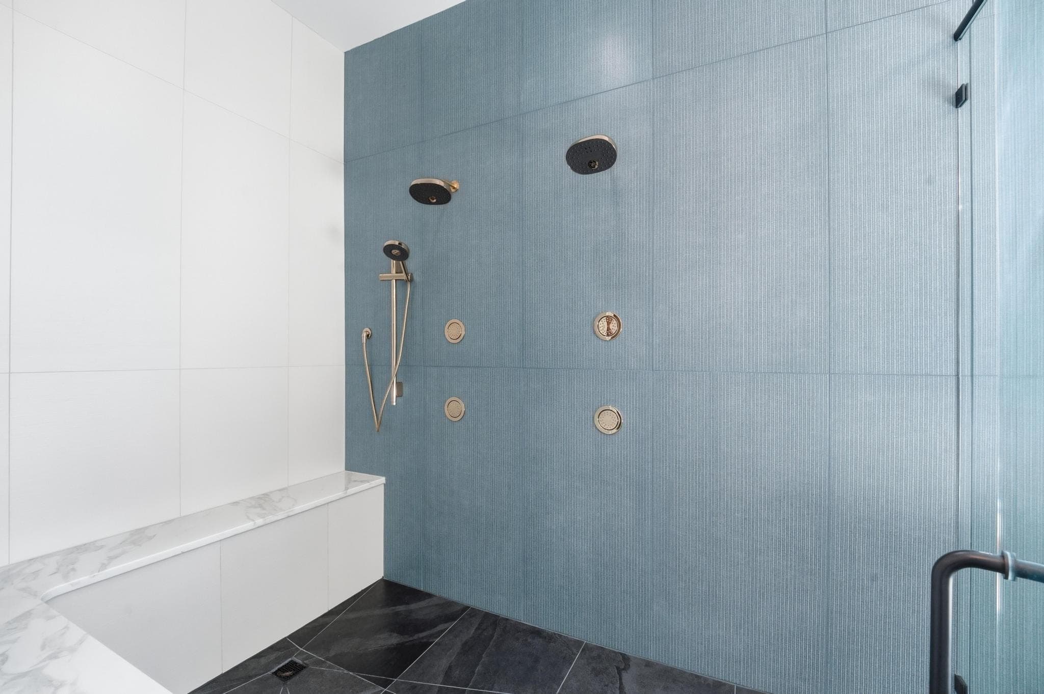 Primary shower with blue tile and brass fixtures