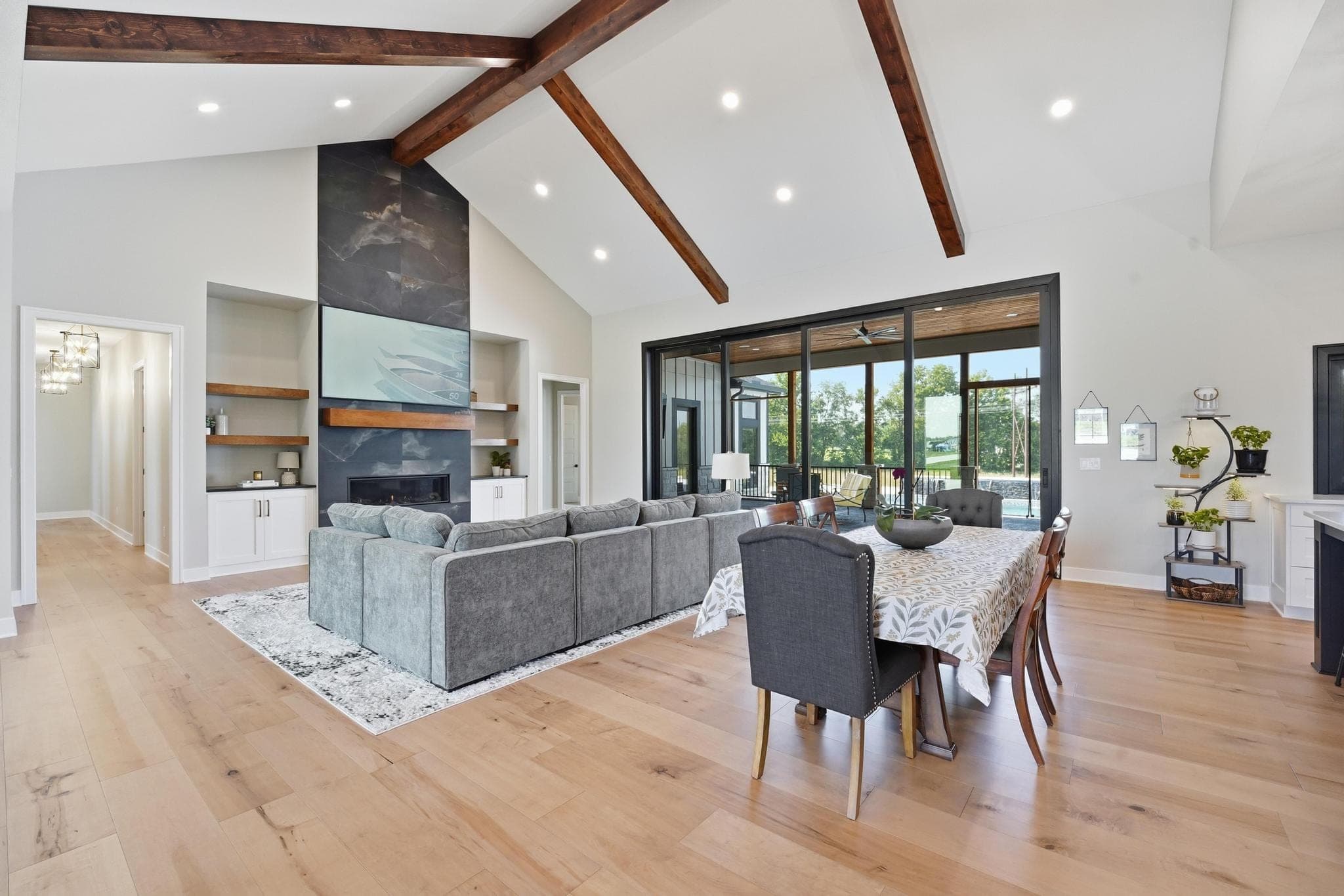 Vaulted great room with exposed beams, slate fireplace and dining beyond