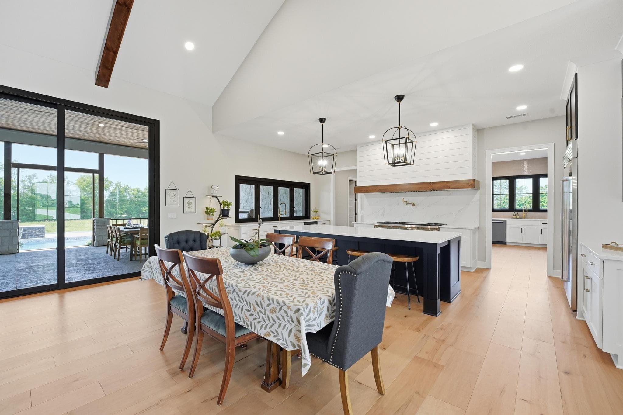 Open kitchen and dining with black island and lantern pendants