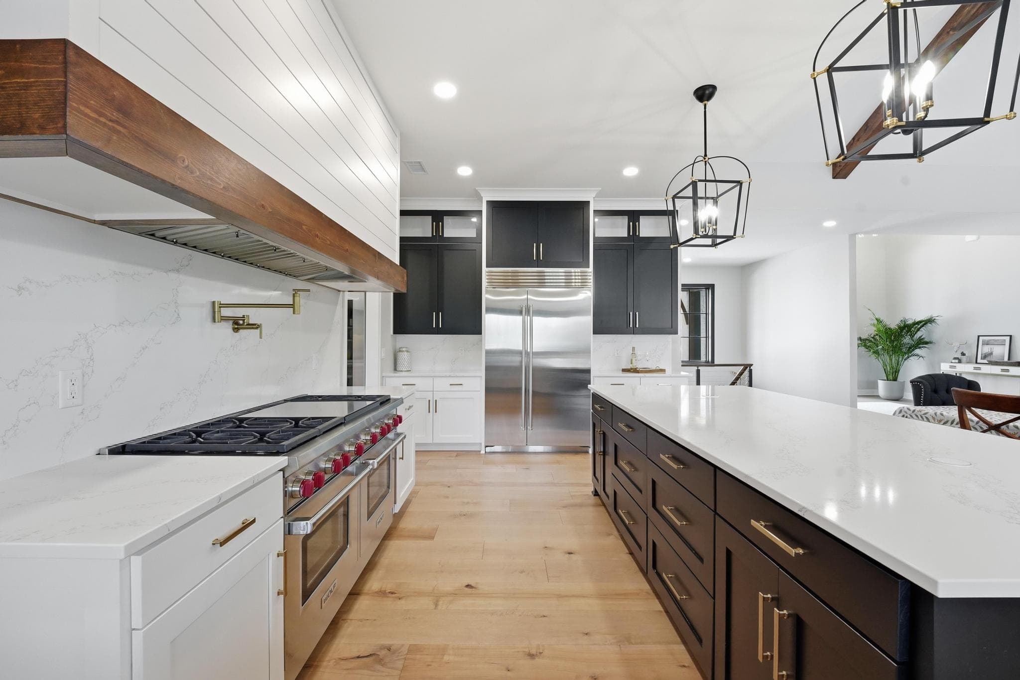 Marble range wall with a wood-wrapped hood and black upper cabinets