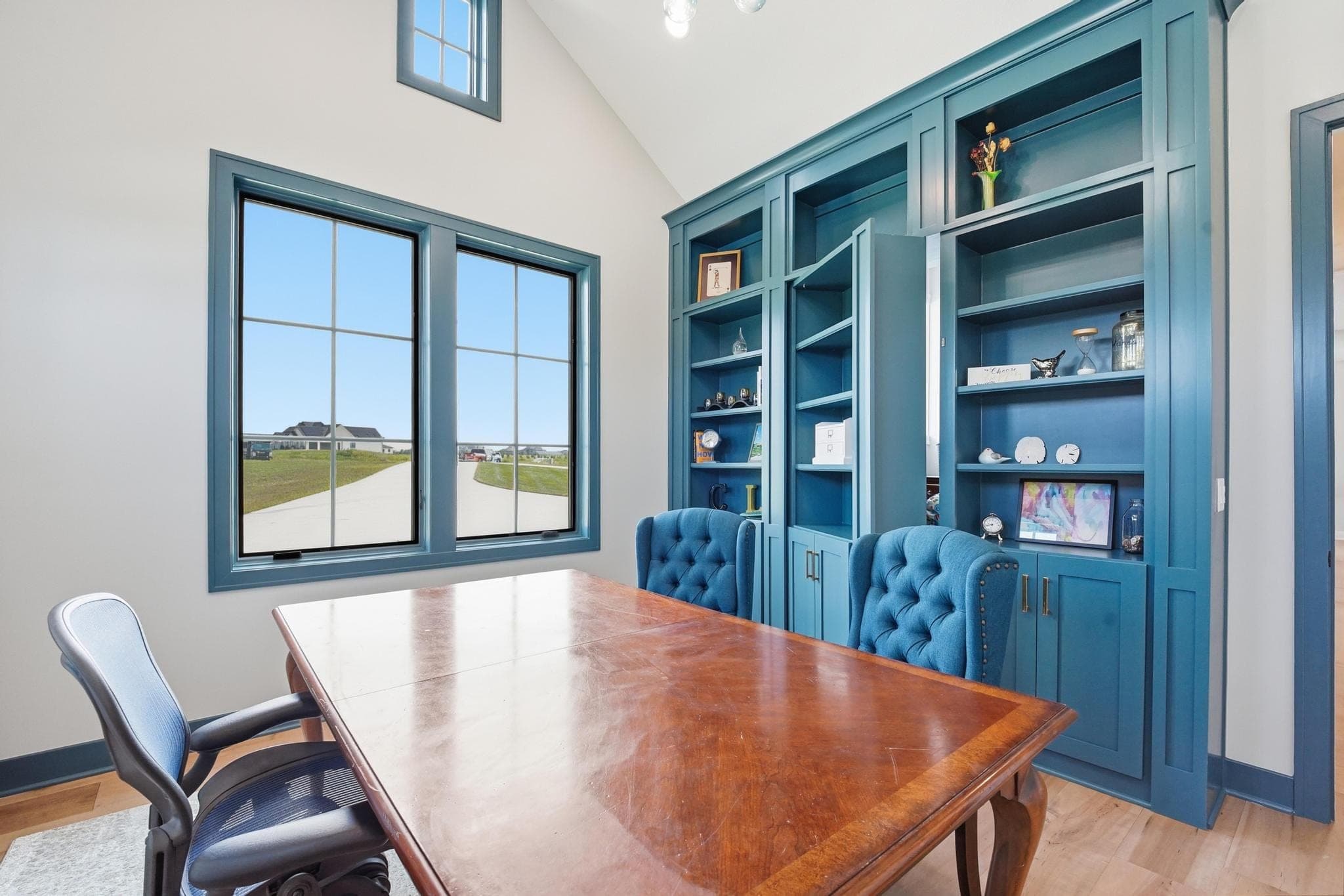 Office with blue built-in bookcases and a wood desk