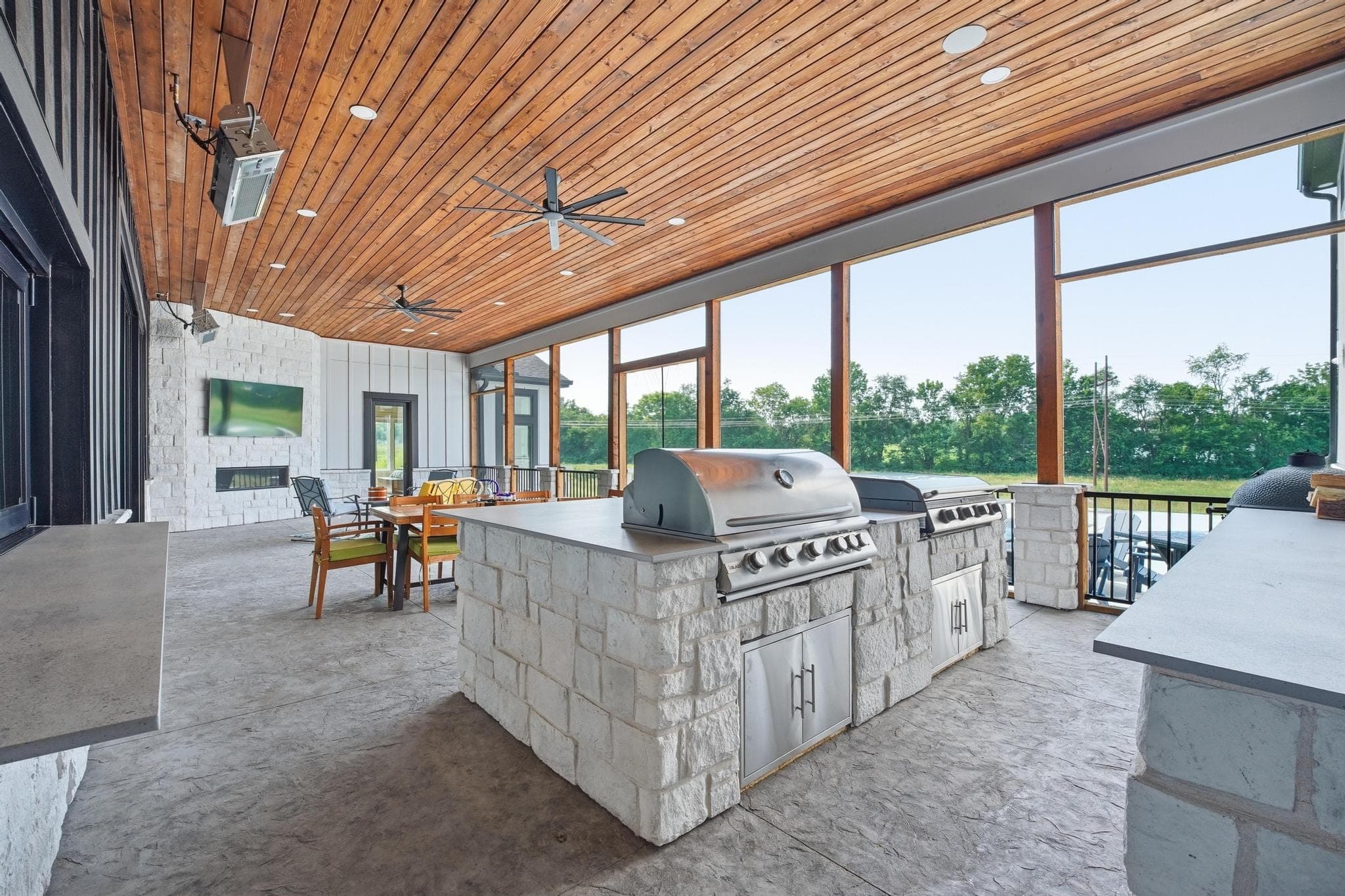 Covered patio outdoor kitchen with a stone island and grill