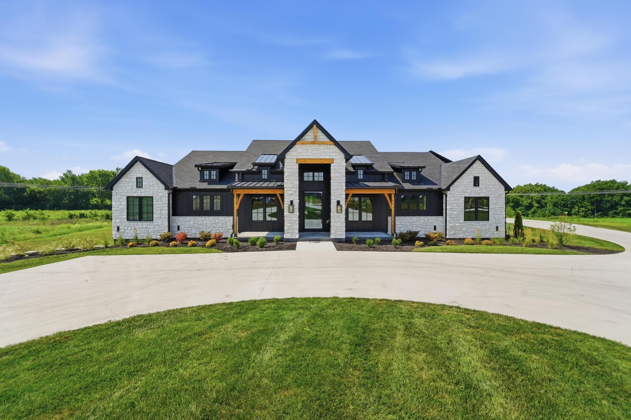 Front elevation of a white stone and black modern farmhouse with a timber-framed entry