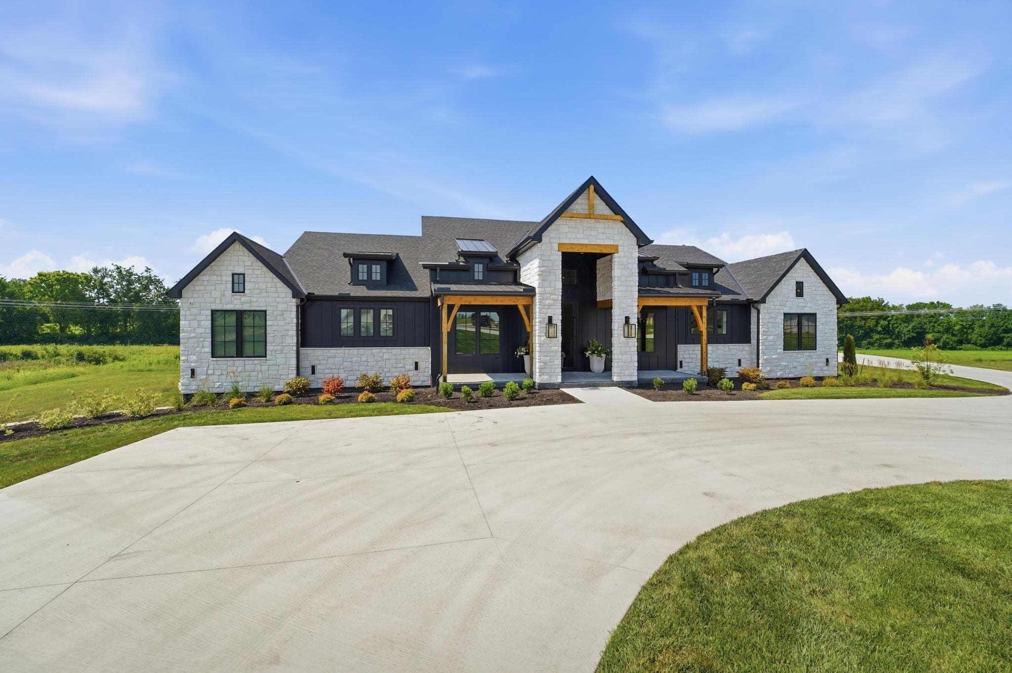 Modern farmhouse front elevation seen from the side of the circular drive