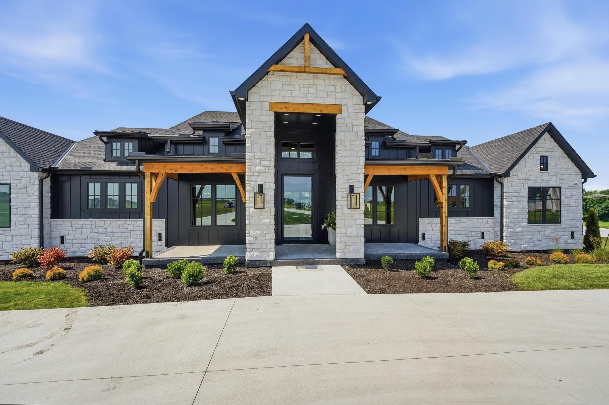 Timber-framed front entry with stone columns and a black-framed glass door