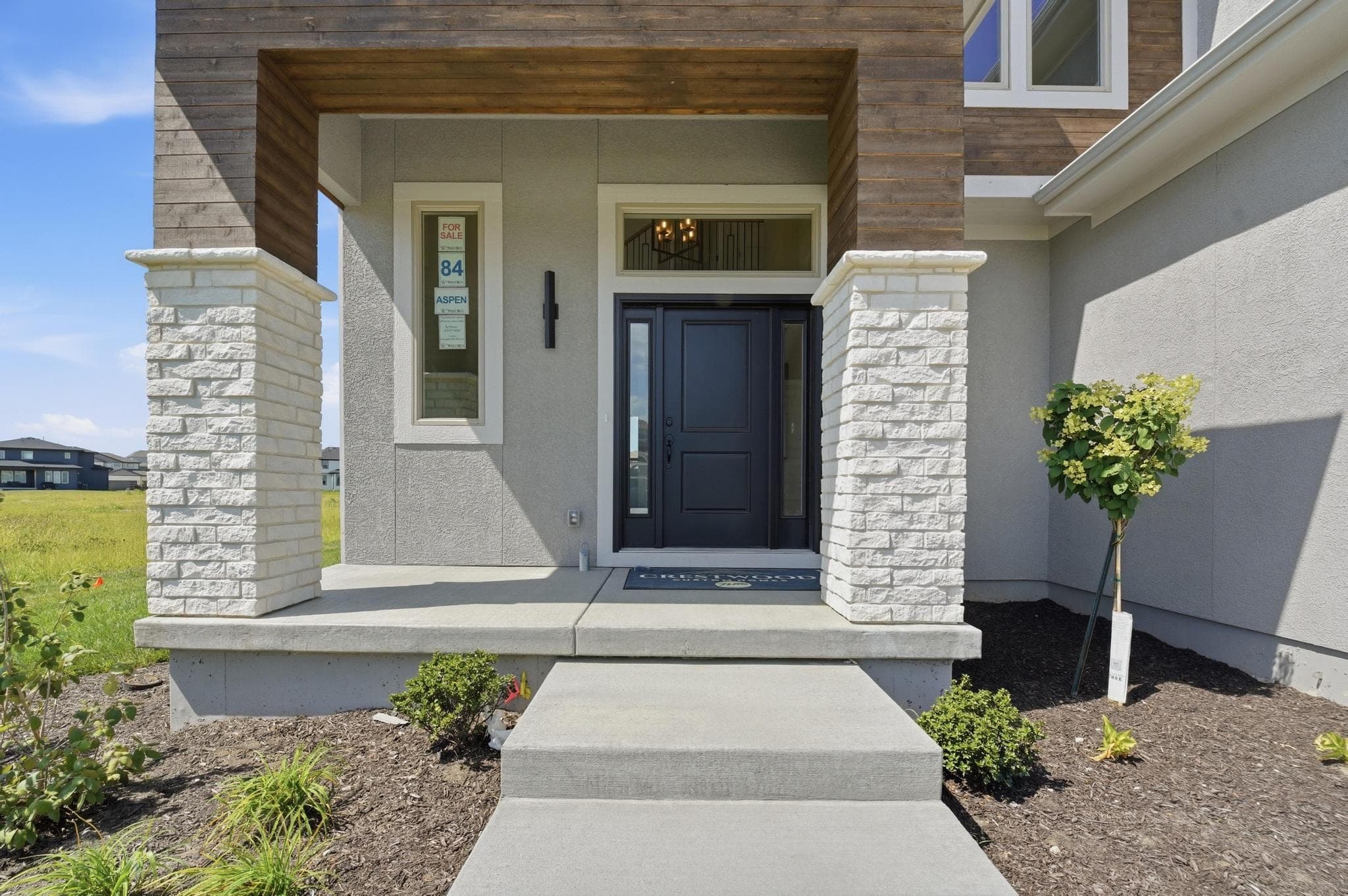 Covered front porch with stone columns and a dark front door