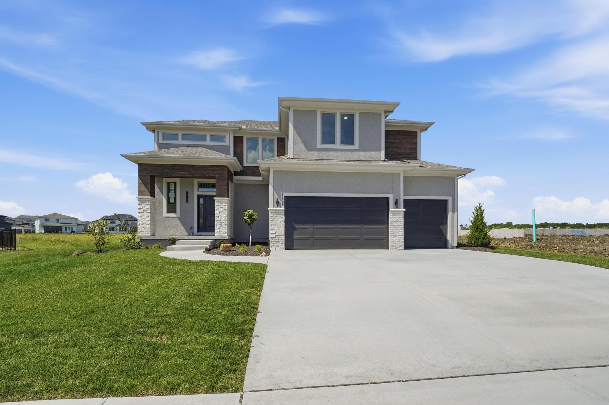 Two-story model home with stone accents and a three-car garage